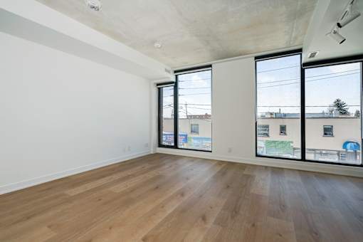 Empty room with wooden floor and sliding glass doors.