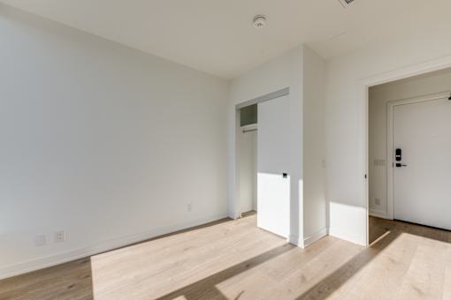 A room with white walls and wooden flooring with two doors.