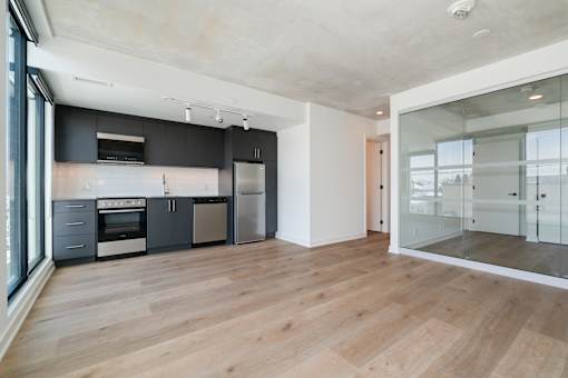 A modern kitchen with wooden floors and a glass wall.