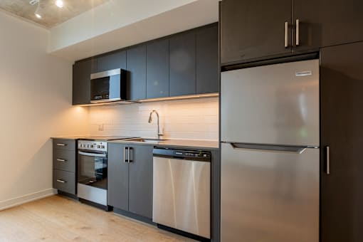 A modern kitchen with stainless steel appliances and dark brown cabinets.