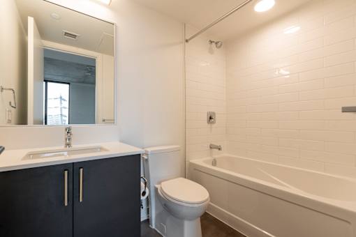A white bathroom with a black cabinet and a white toilet.
