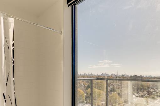 A bathroom with a shower curtain and a view of the city.
