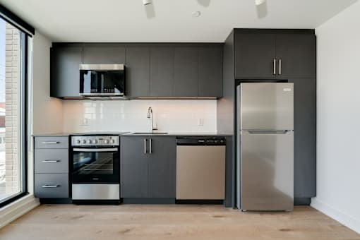 A modern kitchen with a stainless steel refrigerator and oven.