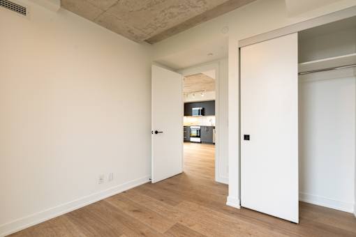 A white door is open to a hallway with wood floors.