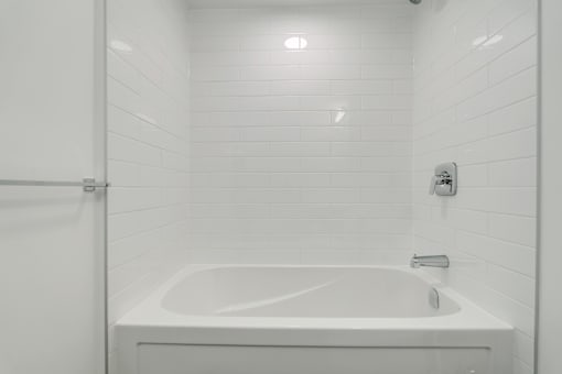 A white bathroom with a white tub and a white shower curtain.