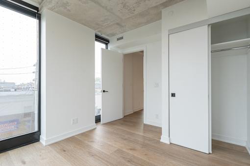A room with white walls and wooden floors, with a door on the right side.