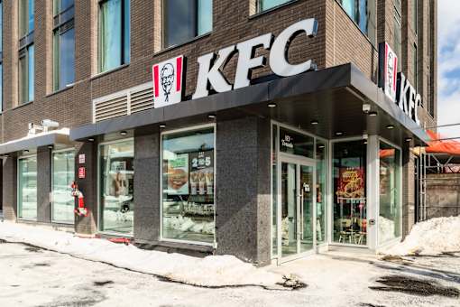A KFC restaurant with a snowy sidewalk in front.