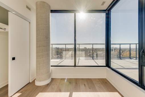 A sunny day in a room with a view of a cityscape through large windows.