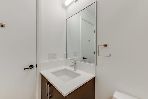A white sink in a bathroom with a mirror above it.