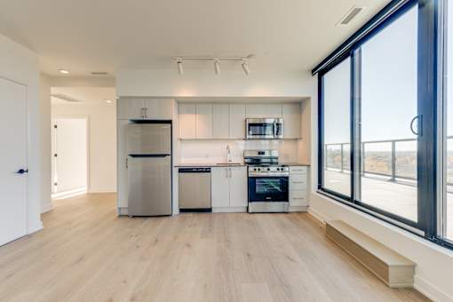 A modern kitchen with wooden floors and stainless steel appliances.