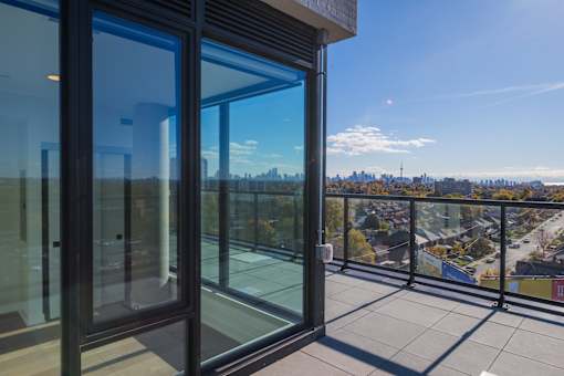 A balcony with glass doors overlooking a cityscape.