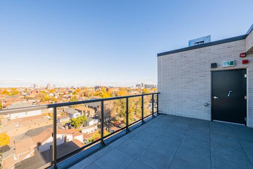 A balcony with a black door and a view of a residential area.