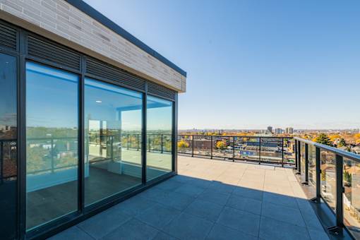 A balcony with glass doors overlooking a cityscape.