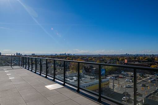 A balcony with a view of a parking lot and buildings.