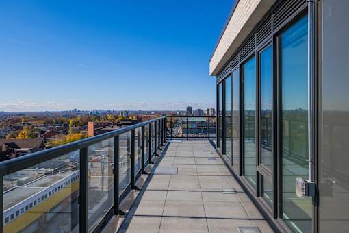 A balcony with glass railings overlooks a cityscape.