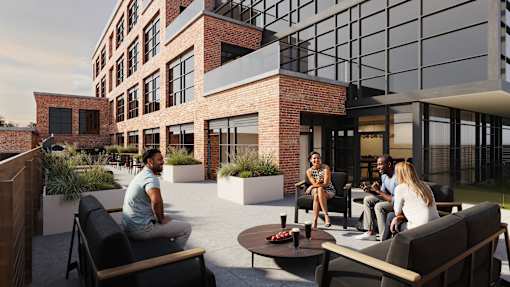 A group of people are sitting on a patio outside a modern building.
