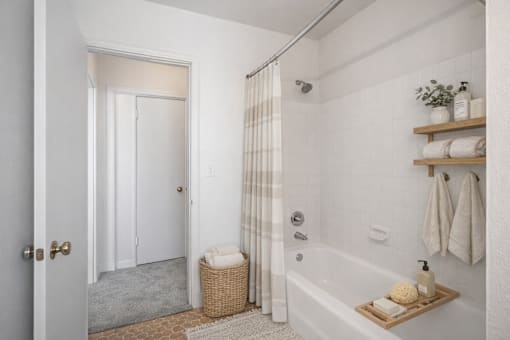 A bathroom with a white tub, a white door, and a white wall.