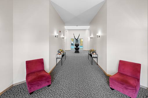 A hallway with two red chairs on either side and a statue in the middle.
