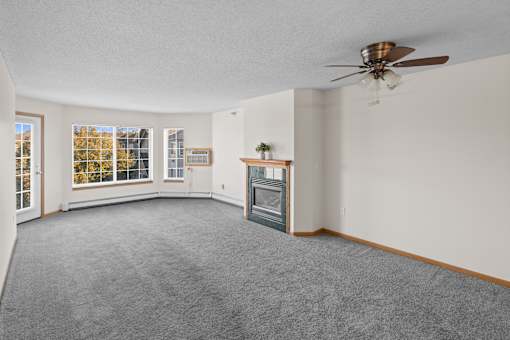 A spacious living room with a fireplace and a ceiling fan.
