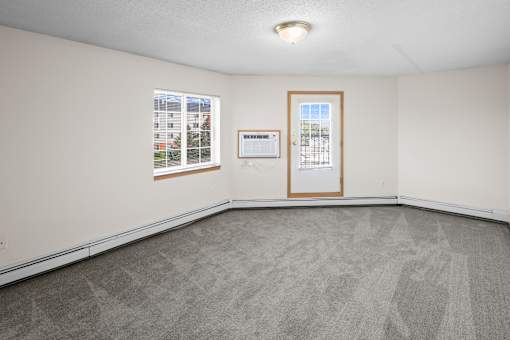 A room with a carpeted floor, a window, and a door.
