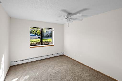 A room with a window and a ceiling fan.