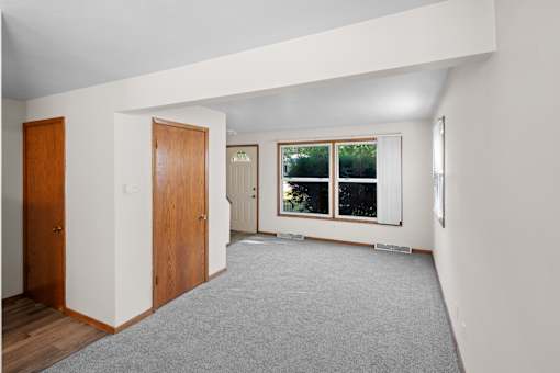 A room with a grey carpet and wooden doors.