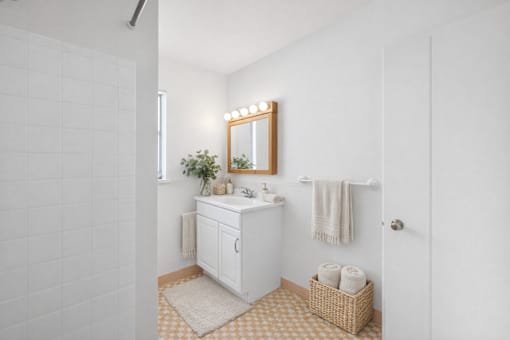 A white bathroom with a sink, mirror, and towel.