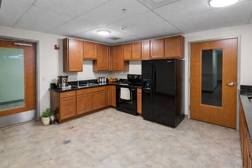 A kitchen with black appliances and wooden cabinets.