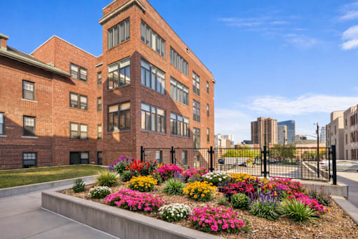 A red brick building with a flower bed in front.