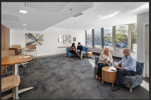 A group of people are sitting in a room with a large window.
