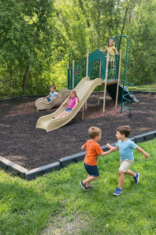 Two young boys are playing on a slide in a playground.