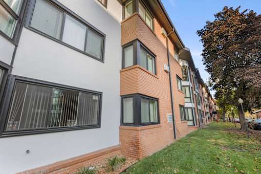 A building with a white and brick facade has windows on the side.