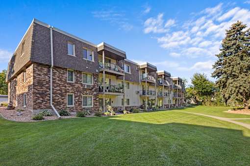 A large, multi-story residential building with a mix of stone and siding exterior.