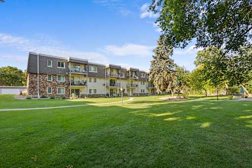 A large grassy area in front of a multi-story apartment building.
