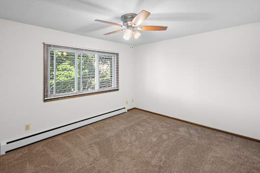 A room with a ceiling fan and a window with blinds.