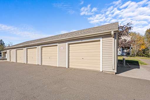 A long building with a grey roof and tan garage doors.