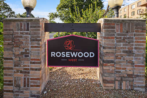 A sign that says Rosewood West is displayed on a brick wall.