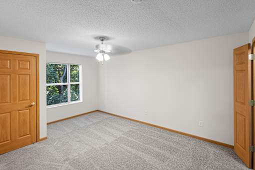 A room with a carpeted floor and a ceiling fan.