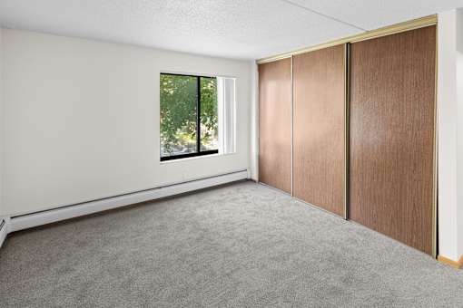 A room with a window and a brown wardrobe.