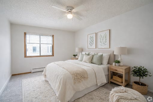 A bedroom with a large bed, a window, and a ceiling fan.