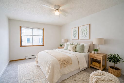 A bedroom with a large bed, a window, and a ceiling fan.