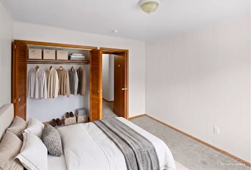 A bedroom with a large bed and a wooden wardrobe.