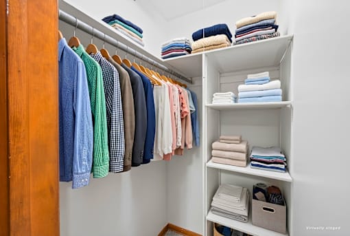 A closet with a variety of shirts and towels.
