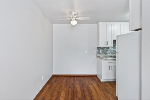 A room with a ceiling fan and wooden floors.