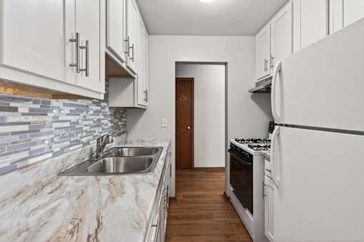 A kitchen with white cabinets and a marble countertop.
