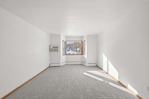 A spacious room with a window and a carpeted floor.