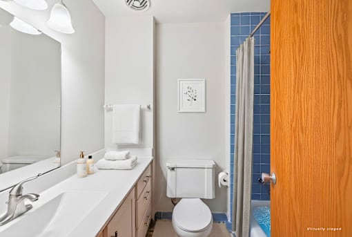 A white toilet with a towel bar and a white sink with a mirror above it.
