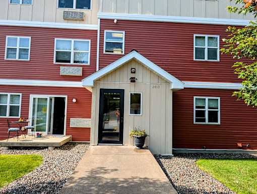 the front entrance of a red house with a porch