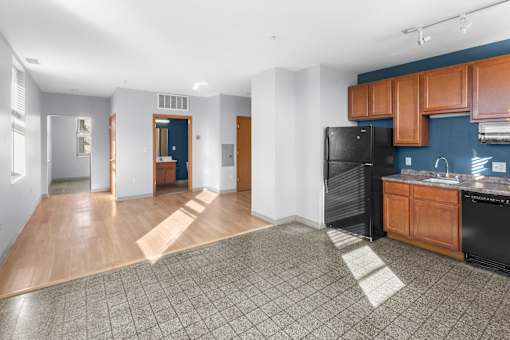 a living room with a kitchen and a black refrigerator