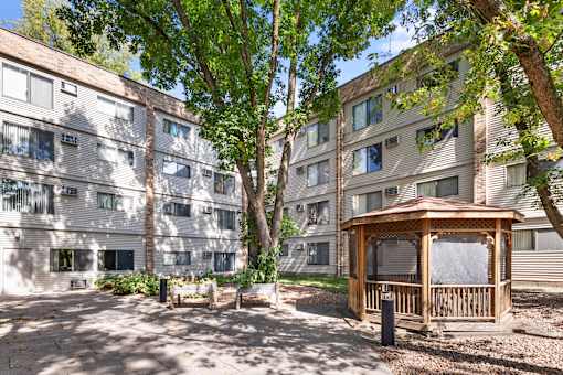 A gazebo sits in the middle of a courtyard between two apartment buildings.